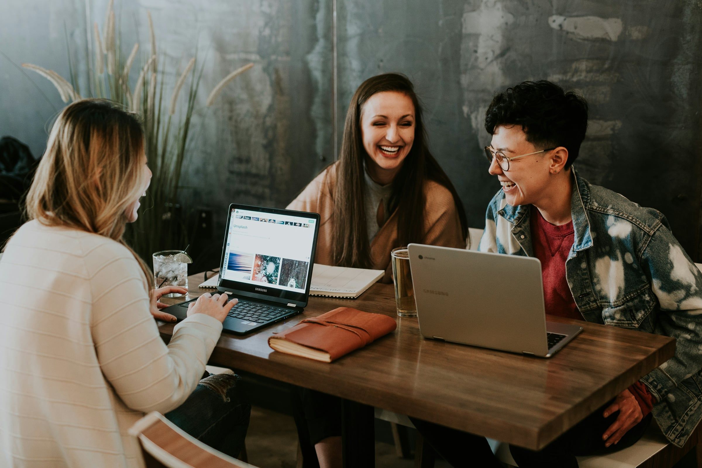Drie collega's in gesprek aan een tafel met laptops.